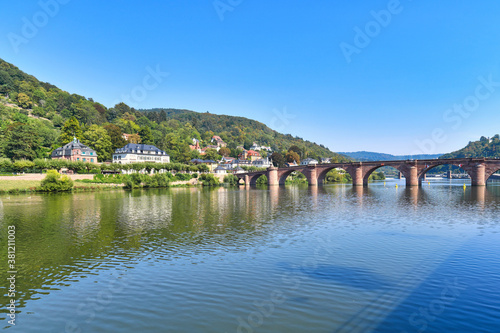View of bridge called 'Karl Theodor Bridge', also known as the Old Bridge, an arch bridge in city Heidelberg in Germany that crosses the Neckar river with Odenwald forest in background