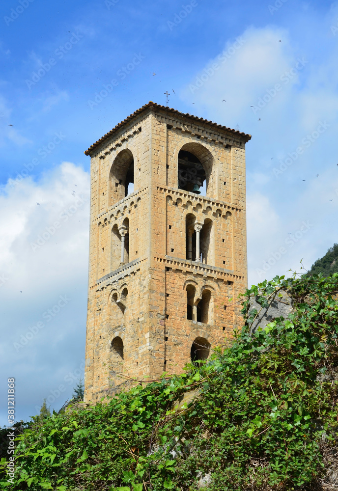 BEGET, CATALONIA, SPAIN, EUROPE, SEPTEMBER 2020. Fantastic tower in the Romanesque church of San Cristóbal surrounded by greenery in the beautiful medieval town of Beget