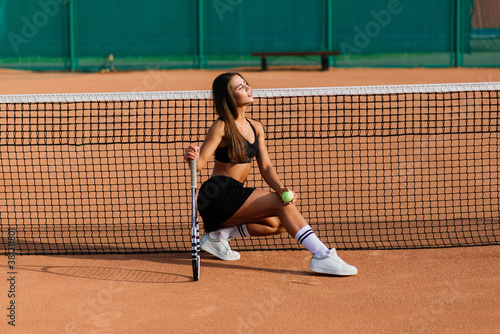 Beautiful stylish sexy woman in black trendy sportswear on tennis court.