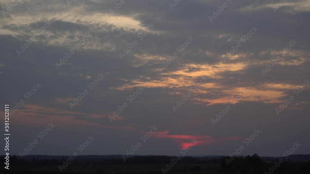 Evening the colorful cloudy sky at the sunset time. The picturesque landscape with a visible horizon line and woods silhouettes. Evening the colorful cloudy sky at the sunset time. The picturesque landscape with a visible horizon line and woods silhouettes.