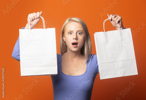 Surprsied blonde in blue blouse with shopping bags photo