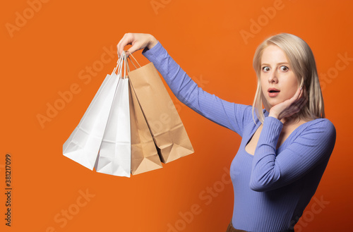 Surprsied blonde in blue blouse with shopping bags photo