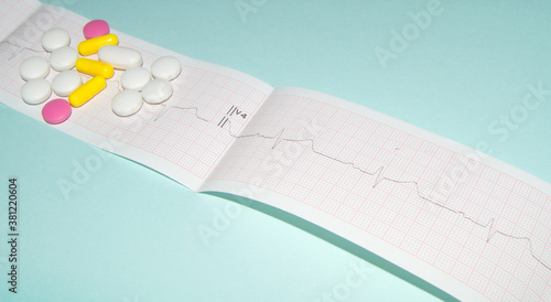 Medications in the form of tablets for oral administration against the background of an electrocardiogram. The heartbeat is shown on the graph, blue background