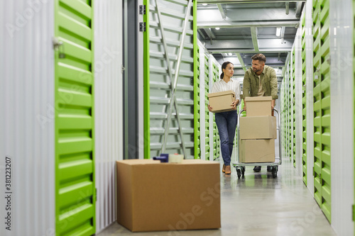 Billede på lærred Full length portrait of young couple holding cardboard boxes walking towards cam