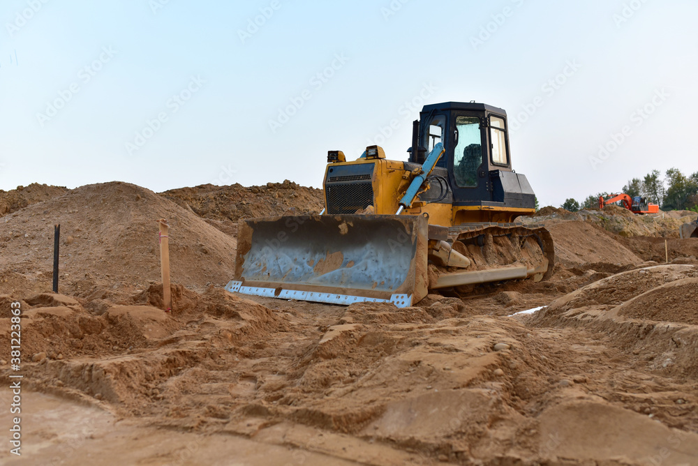 Dozer on earthmoving at construction site. Bulldozer on road work. Construction machinery and equipment on groundwork.