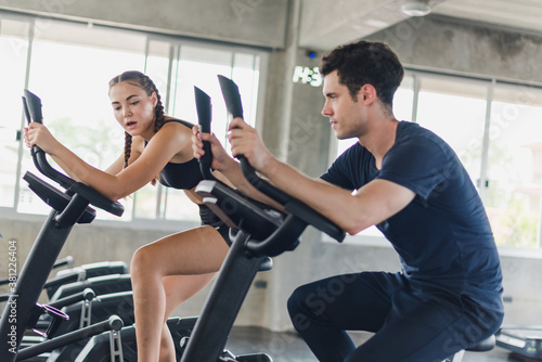 Male and female athletes talk about exercise, cycling in the gym. They wear sportswear to exercise.