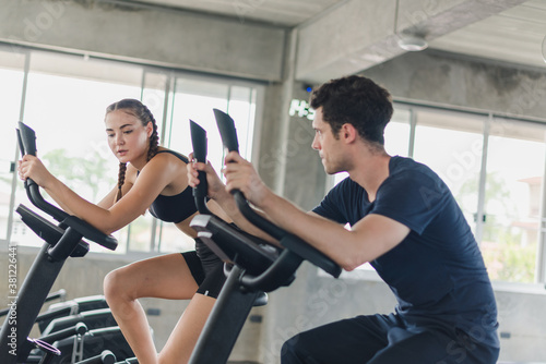 Male and female athletes talk about exercise  cycling in the gym. They wear sportswear to exercise.