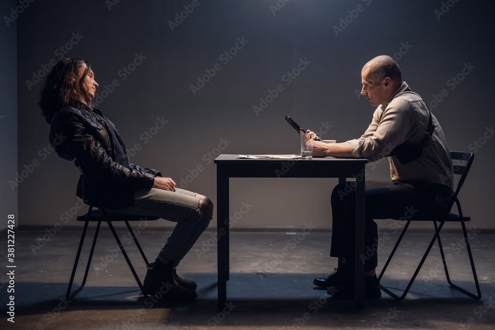 In the interview room, a handcuffed suspect meets with a police or FBI detective investigator without a lawyer In the interview room, a handcuffed suspect meets with a police or FBI detective investigator without a lawyer