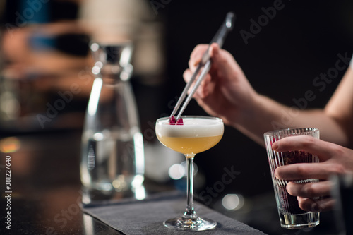 Close-up of a glass with a beautiful delicious cocktail standing on the table in a restaurant. The bartender creates an alcoholic drink for women.