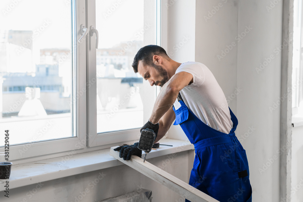 A man in blue work clothes stands against the wall and showing thumb A man in blue work clothes stands against the wall and showing thumb