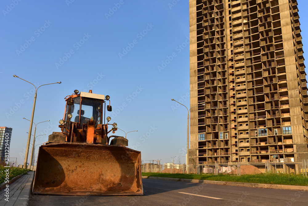 Wheel loader with a bucket on a street in the city during the construction of the road. Construction site with heavy machinery for road work. Front end loader on road building. Civil engineering