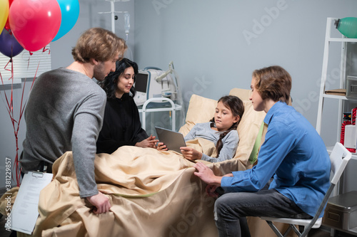 A family showing a little sick girl her medical results using a digital tablet, the results are good.