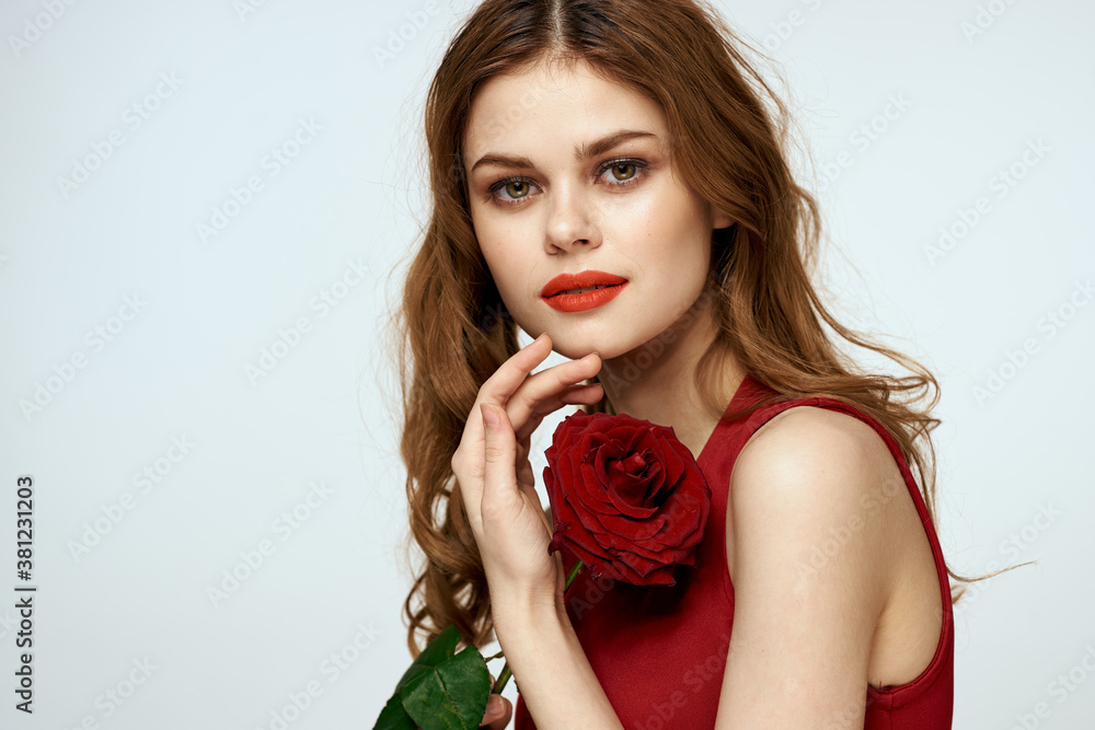 Beautiful woman in a red dress holds a rose in her hand a gift flowers decoration attractive look Beautiful woman in a red dress holds a rose in her hand a gift flowers decoration attractive look