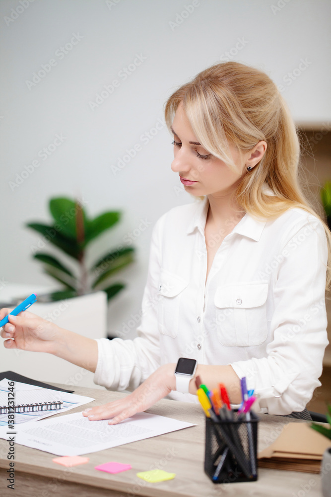 Business woman sitting at desk in office and examines documents Business woman sitting at desk in office and examines documents