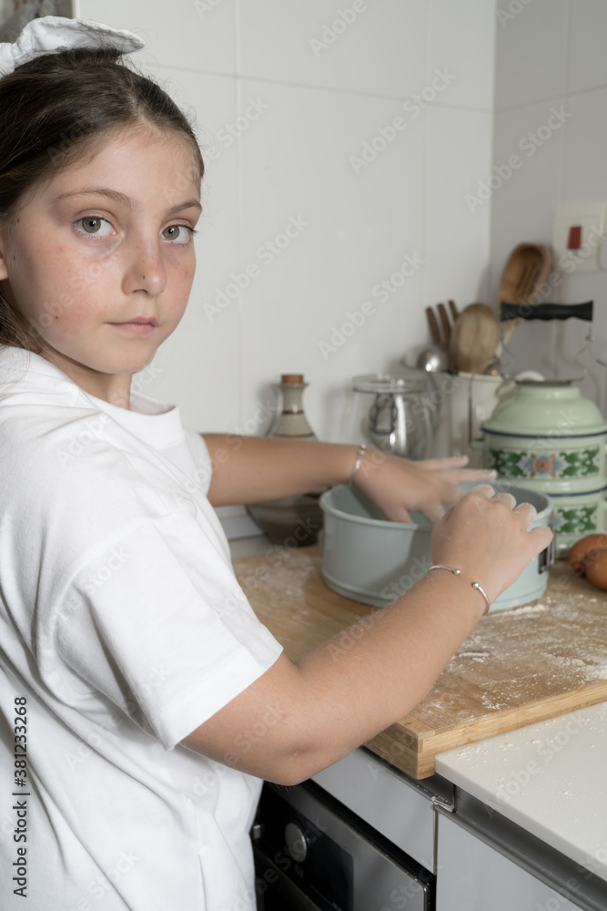 Cute Caucasian Girl Baking in the kitchen using a blue vintage tin Cute Caucasian Girl Baking in the kitchen using a blue vintage tin