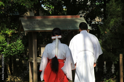小さな神社に参拝する神職(神主)と巫女