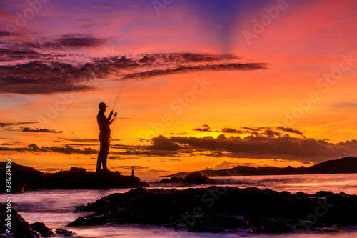 Silhouette of motion Blur Fisherman during sunset with colorful sky burst in background