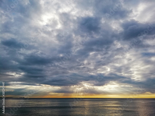 Beautiful cloudy sunset in the Caribbean Sea  the sunset produces yellow and orange colors  cargo ships are seen on the horizon.