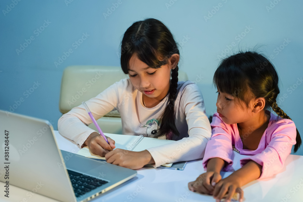 Two young girl use laptops to study online at home during the coronavirus (COVID-19) outbreak, an epidemic quarantine concept. Two young girl use laptops to study online at home during the coronavirus (COVID-19) outbreak, an epidemic quarantine concept.