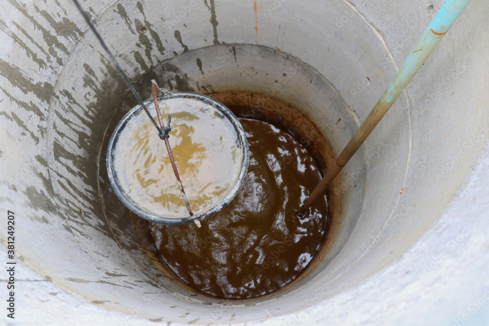 pulling out bucket full of drink water from the well, view of the water