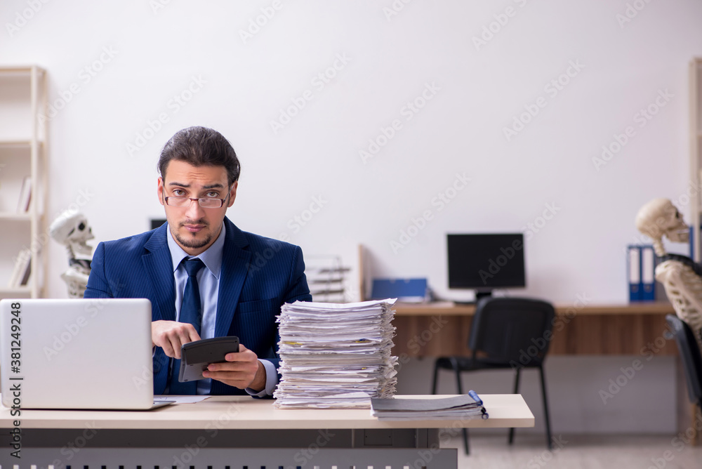 Young male employee with skeletons in the office Young male employee with skeletons in the office