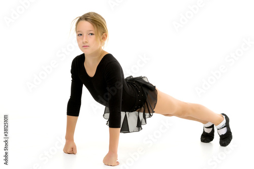 The little gymnast perform an acrobatic element on the floor.