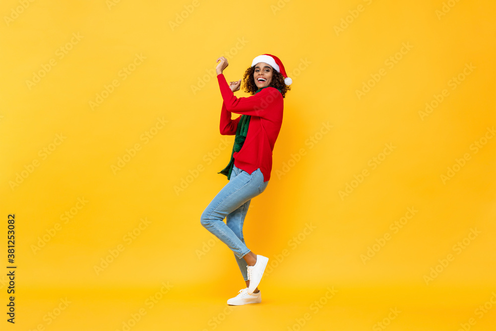 Full length portrait of fun happy woman in Christmas attire dancing on isolated yellow studio background