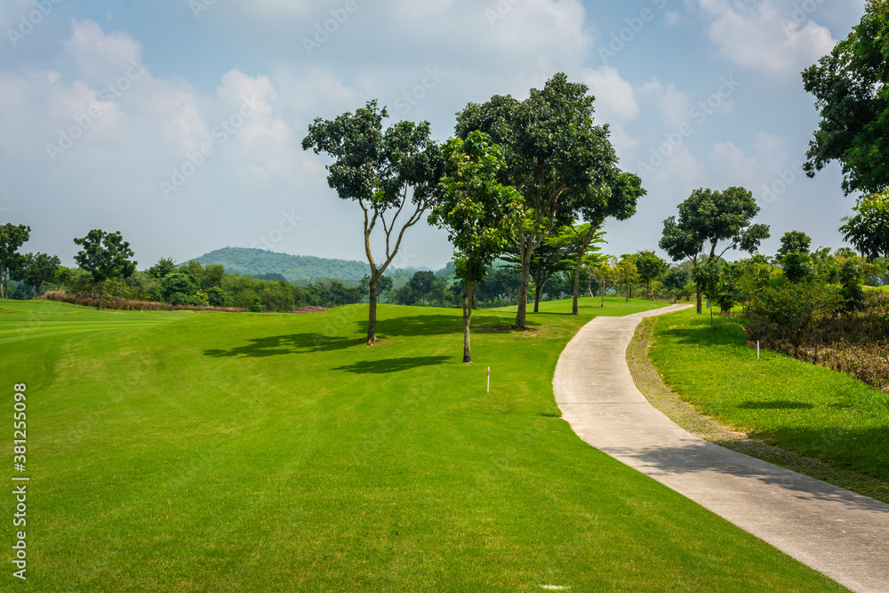 The road way for golf cart and golfer  in golf course with green grass ,green trees blue sky white clouds background