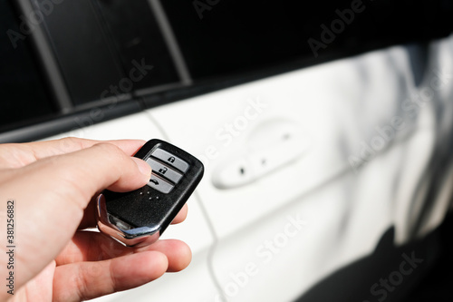 Fototapeta Naklejka Na Ścianę i Meble -  Man hand holding the car remote, he push theopen the car door remote control to