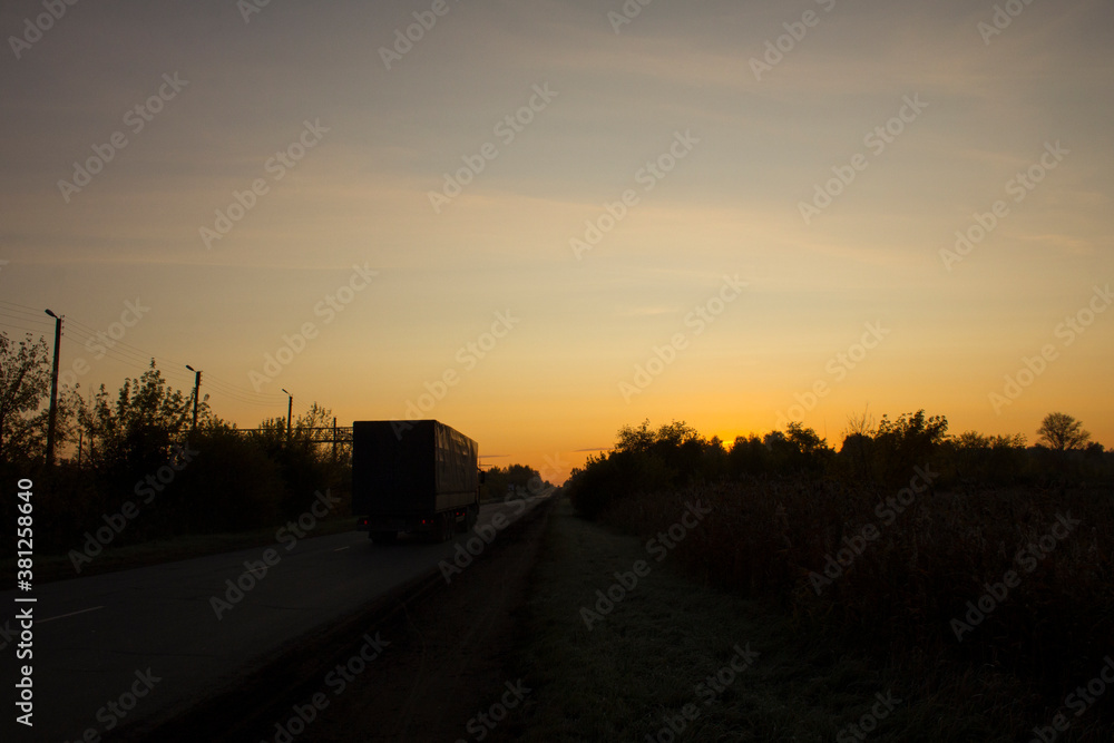 A large trailer drives along the highway towards dawn A large trailer drives along the highway towards dawn