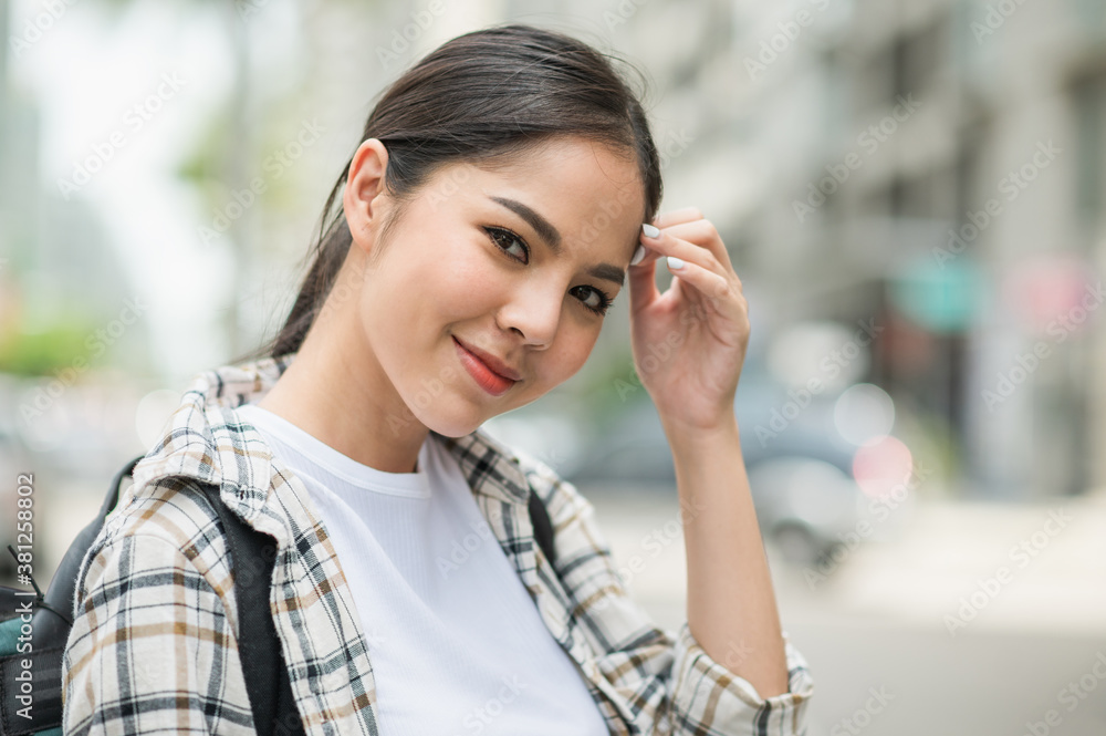 Smiling young asian beautiful woman backpacker traveling take time in holiday in urban city avenue. She walking alone the downtown area.