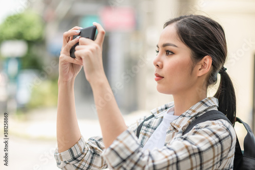 Young Asian beautiful woman travelers use her mobile phones to take the photo of view urban city downtown.