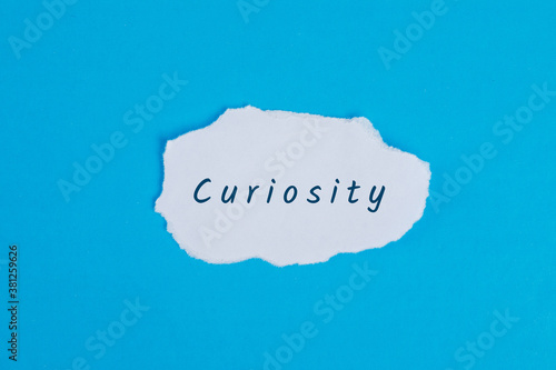 Business concept with curiosity word on torn paper on blue background flat lay.