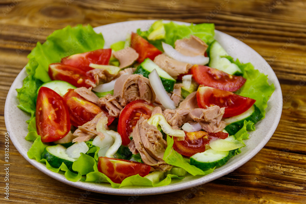 Tasty tuna salad with lettuce and fresh vegetables on wooden table Tasty tuna salad with lettuce and fresh vegetables on wooden table