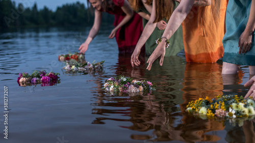 Lovely girls in flower wreaths in nature. Ancient pagan origin celebration concept. Summer solstice day. Mid summer. Ancient rituals. photo