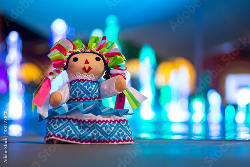 Muñeca de trapo tradicional mexicana, fondo con chorros de agua de colores