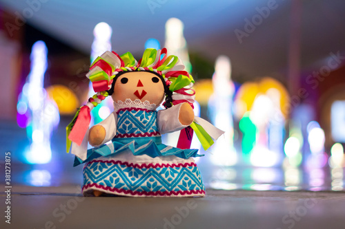 Muñeca de trapo tradicional mexicana, fondo con chorros de agua de colores