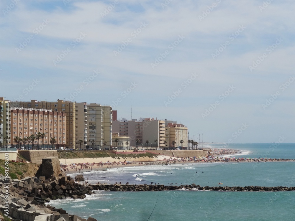 夏の青い海とビーチ、ビーチ沿いに建物が並ぶ風景、スペインカディス・ラ・カレタビーチ/The landscape of blue shore at la Caleta beach in Cadiz, Spain