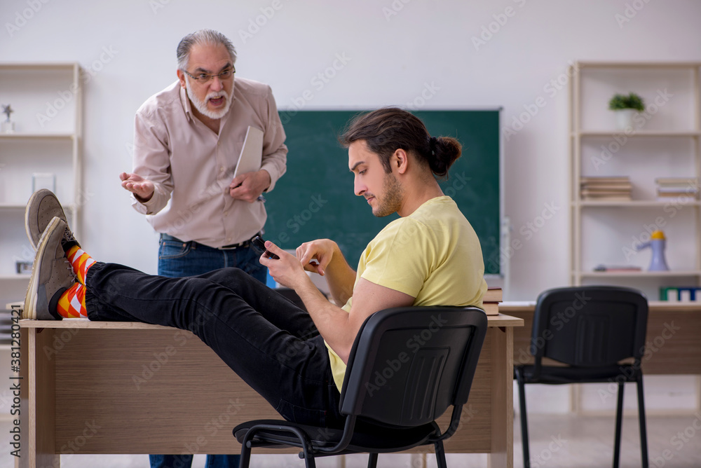 Old teacher and young male student in the classroom Old teacher and young male student in the classroom
