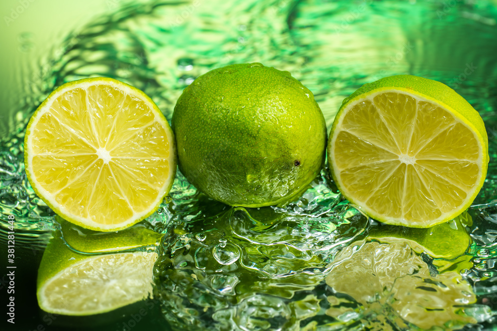 whole lime and two halves with splashing water on gradient background whole lime and two halves with splashing water on gradient background
