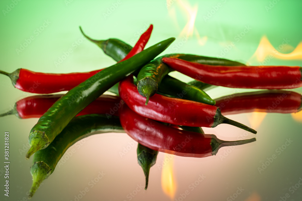 hot red and green peppers burning in chili fire on gradient background hot red and green peppers burning in chili fire on gradient background