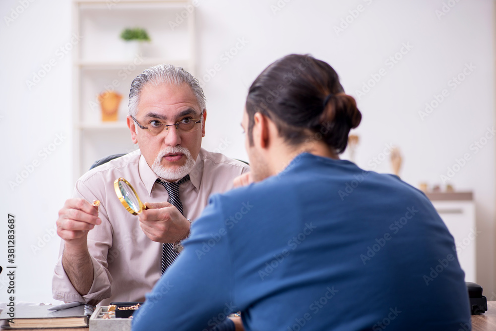 Young man visiting old male jeweler Young man visiting old male jeweler