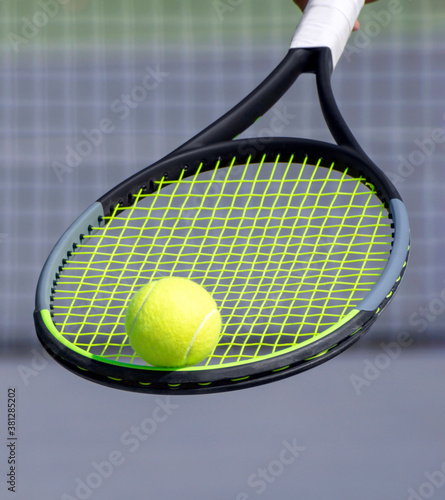 Tennis ball on tennis racket and blurred tennis court in background. Sport game and active healthy lifestyle concept. Close up