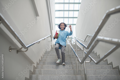 Excited schoolboy running downstairs with pile of books