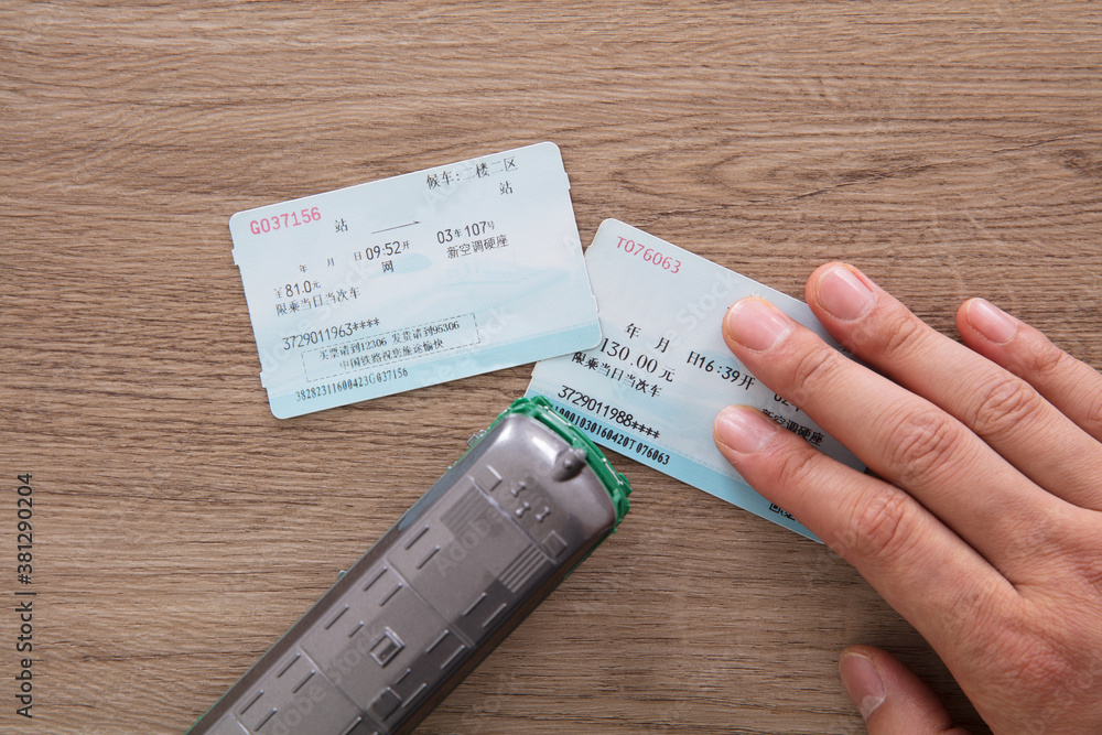 Holding a train ticket to home and a small train model on the table Holding a train ticket to home and a small train model on the table