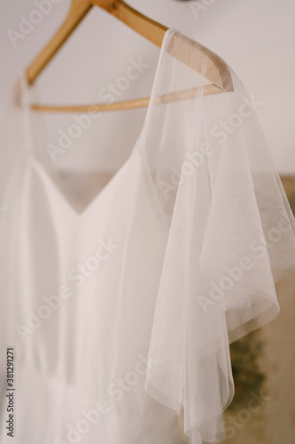 Close-up of the top of the bride's dress on a wooden hanger.