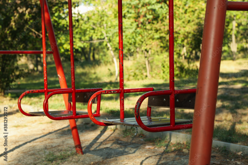 Red swings in city park in bright sunny morning Red swings in city park in bright sunny morning