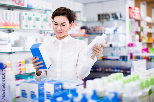 Pretty woman customer browsing rows of drugs in pharmacy
