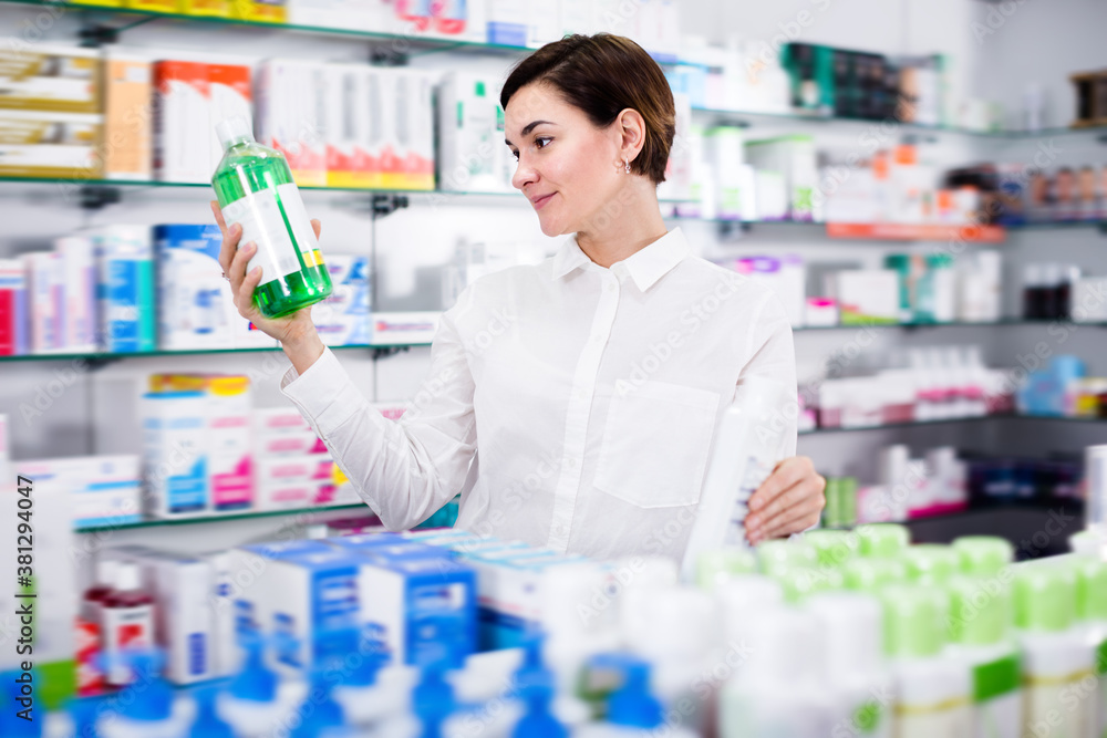 Happy woman customer browsing rows of drugs in pharmacy