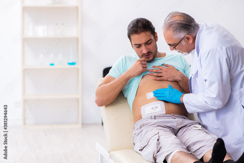 Injured young man visiting experienced male doctor Injured young man visiting experienced male doctor